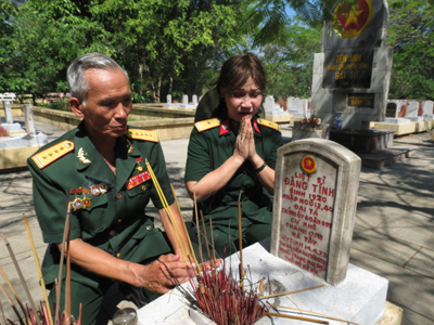 Ông Sinh cùng cô văn công Trường Sơn Vũ Thúy Lành bên mộ liệt sỹ đại tá Đặng Tính, Chính ủy Đoàn 559, Bộ đội Trường Sơn.