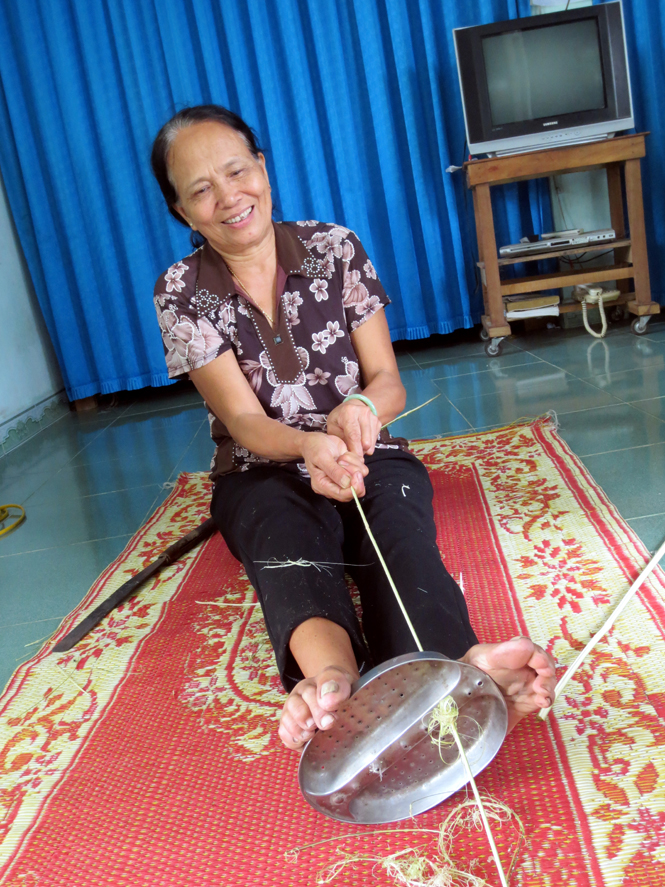 Bà Bùi Thị Bưởi minh hoạ cách vót một vành nón lá bằng dụng cụ vót vành thủ công do chính tay chồng bà làm vào năm 1976.