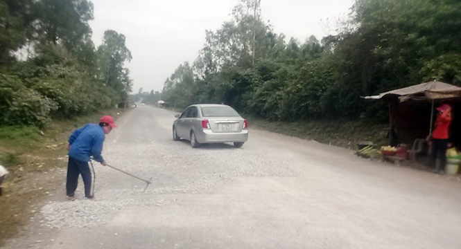 Người dân trên đoạn đường này khắc phục tình trạng xe chở vật liệu rơi vãi xuống đường. (Ảnh chụp ngày 4-1-2015).