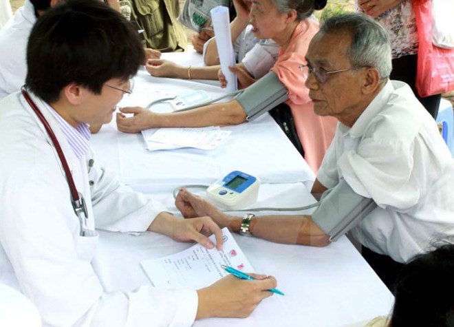  Nhân viên y tế đo huyết áp cho người dân. (Ảnh: TTXVN/Vietnam+)