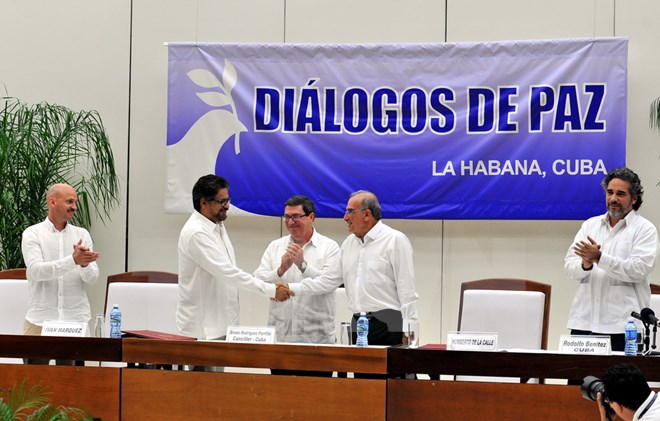 Đại diện của Chính phủ Colombia và FARC bắt tay sau khi được Ngoại trưởng Cuba Bruno Rodríguez (giữa) trao tượng trưng hai phiên bản thỏa thuận. (Ảnh: Lê Hà/TTXVN)