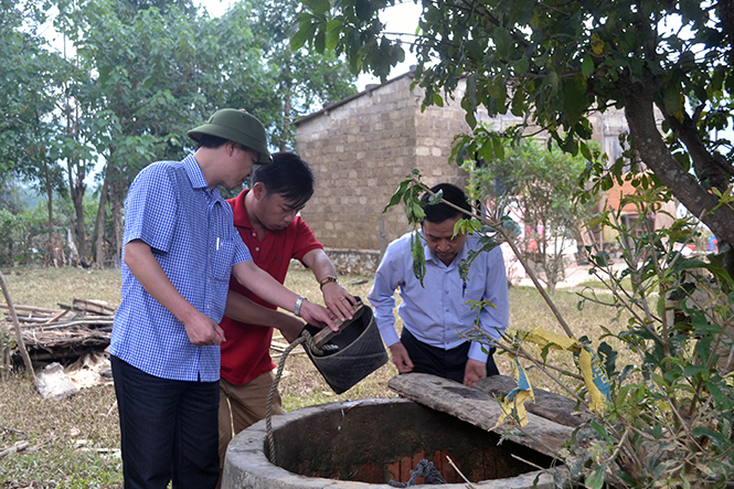 Bác sĩ Nguyễn Đức Cường, Giám đốc Sở Y tế và cán bộ Trung tâm Y tế dự phòng Minh Hóa đang hướng dẫn người dân khử khuẩn nguồn nước.