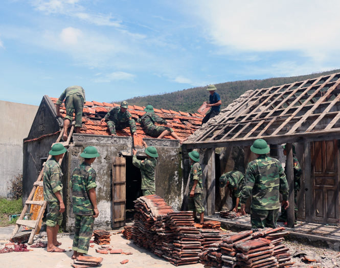 Các cán bộ, chiến sỹ Bộ đội Biên phòng tỉnh giúp người dân thôn Vĩnh Sơn, xã Quảng Đông, huyện Quảng Trạch lợp lại nhà bị tốc mái do bão.     