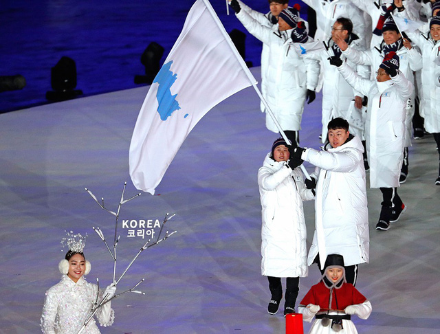 Hai vận động viên Triều Tiên và Hàn Quốc cầm cờ, dẫn đầu đoàn diễu hành chung của hai đoàn - Ảnh: REUTERS