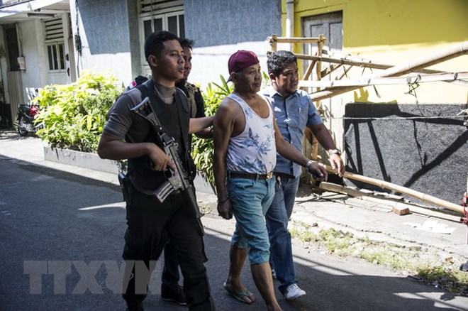 Cảnh sát bắt giữ một đối tượng tình nghi để thẩm vấn sau vụ tấn công ở Surabaya, Indonesia ngày 14-5 vừa qua. (Ảnh: AFP/TTXVN)