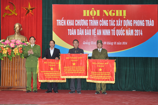 Đại tá Nguyễn Quốc Tường, PGĐ Công an tỉnh thừa ủy quyền của BCA trao cờ cho các đơn vị dẫn đầu phong trào Toàn dân bảo vệ ANTQ năm 2013.