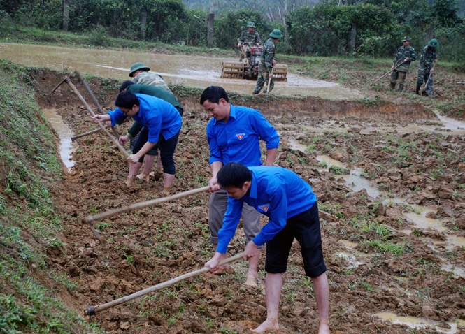  Các đoàn viên thanh niên và cán bộ chiến sĩ Đồn Biên phòng Cà Xèng giúp bà con làm đất để gieo lúa.