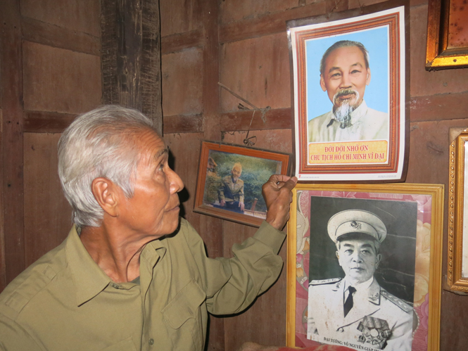 Ông Hồ Nhâm đang treo lại ảnh Bác Hồ và Đại tướng Võ Nguyên Giáp nơi trang trọng nhất trong nhà.
