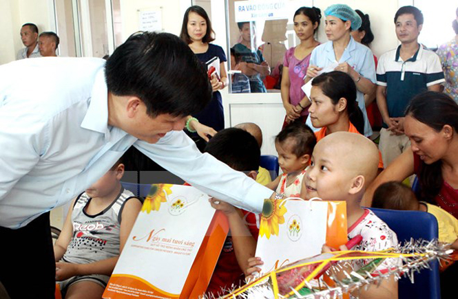 Thứ trưởng Bộ Y tế Nguyễn Thanh Long trao quà cho các bệnh nhi ung thư trong sự kiện diễn ra vào tháng 9-2015.(Ảnh: Dương Ngọc/TTXVN)