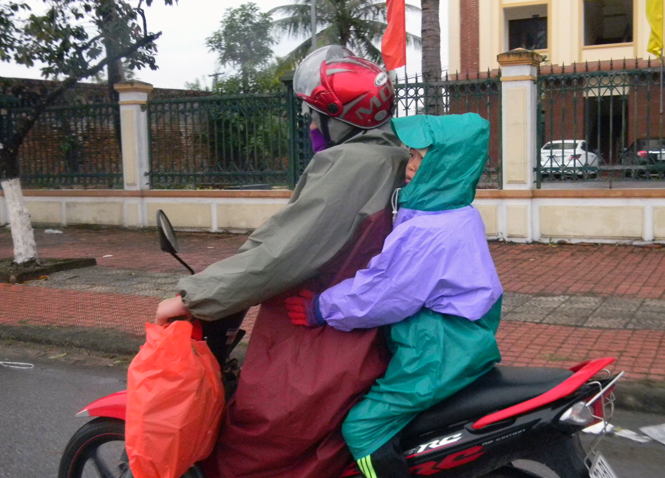 Người lớn và trẻ em vẫn choàng thêm áo mưa để chống rét khi ra đường.