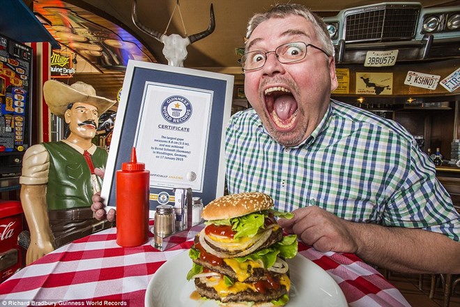  Bernd Schmidt có thể há miệng cực rộng để nuốt chửng cái hamburger. Để có thể đạt được danh hiệu người há miệng to nhất thế giới, ông Schmidt đã đặt một thanh kim loại giữa răng cửa trên và dưới của mình .