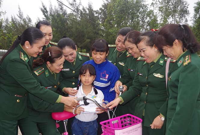 Chị em phụ nữ BĐBP tỉnh trao số tiền nhận đỡ đầu và xe đạp cho em Phan Ngọc Anh Thư.