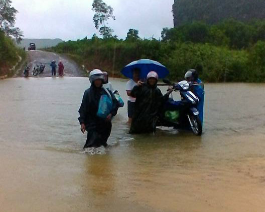 Người dân xã Tân Hóa phải khiêng xe qua những đoạn đường nơi nước ngập sâu