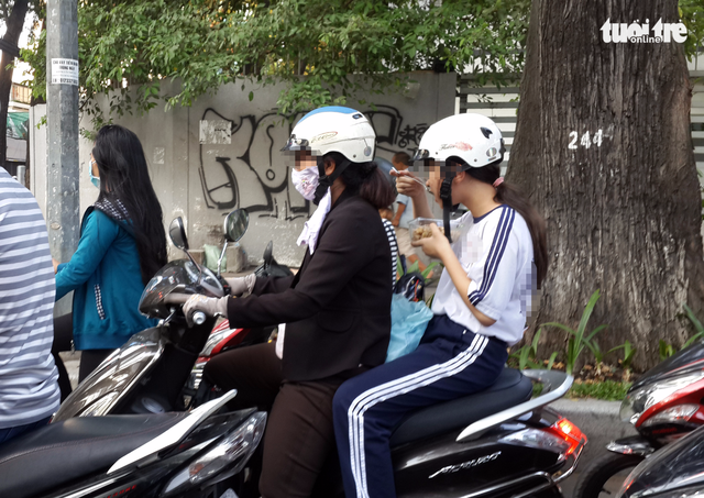  Một nữ sinh TP.HCM ngồi ăn trên xe máy ngay sau giờ học chính khóa buổi chiều - Ảnh: NGỌC HIỂN