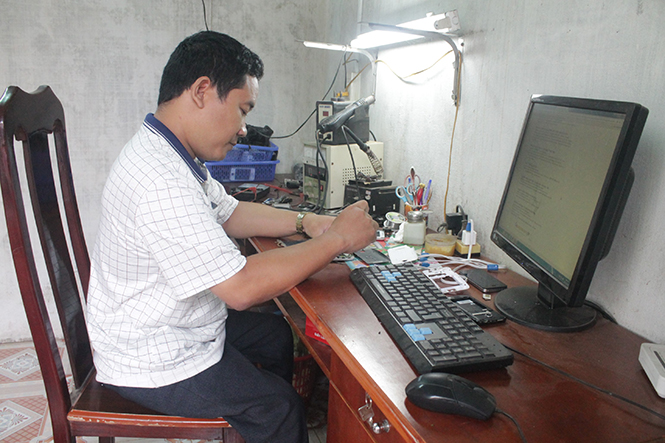 Anh Phạm Văn Nhân đang sửa chữa điện thoại ở cửa hàng của mình trên đường Lê Lợi (TP. Đồng Hới).