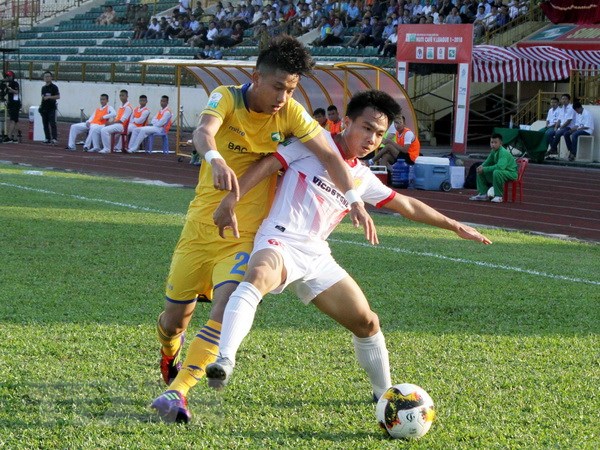 Pha tranh chấp bóng của cầu thủ Sông Lam Nghệ An (áo vàng) và cầu thủ Nam Định (áo trắng). (Ảnh: Tá Chuyên/TTXVN)