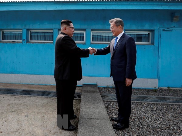 Tổng thống Hàn Quốc Moon Jae-in (phải) và nhà lãnh đạo Triều Tiên Kim Jong-un bắt tay hữu nghị tại đường phân định ranh giới hai miền ở làng đình chiến Panmunjom ngày 27-4. (Nguồn: Yonhap/TTXVN)