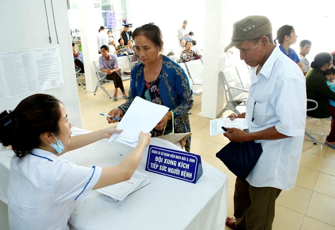  Nhân viên y tế hướng dân người bệnh làm thủ tục khám chữa bệnh. (Ảnh: Dương Ngọc/TTXVN)